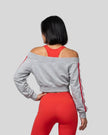 Upper body back view of woman wearing TrackLine Edge Jacket with off-shoulder neckline in Flower Gray over red TrackLine Edge sports bra and matching leggings