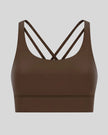 3D product view of the AlignCross Studio Bra in brown, highlighting the scoop neckline and crisscross back straps.