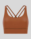 3D product view of the AlignCross Studio Bra in caramel brown, highlighting the scoop neckline and crisscross back straps.