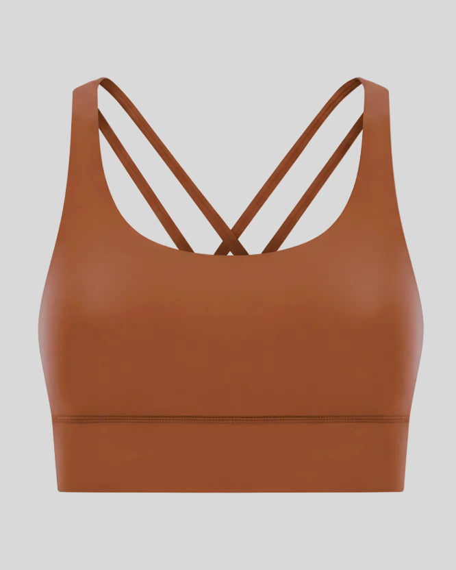 3D product view of the AlignCross Studio Bra in caramel brown, highlighting the scoop neckline and crisscross back straps.