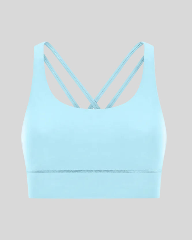 3D product view of the AlignCross Studio Bra in pastel blue, highlighting the scoop neckline and crisscross back straps.