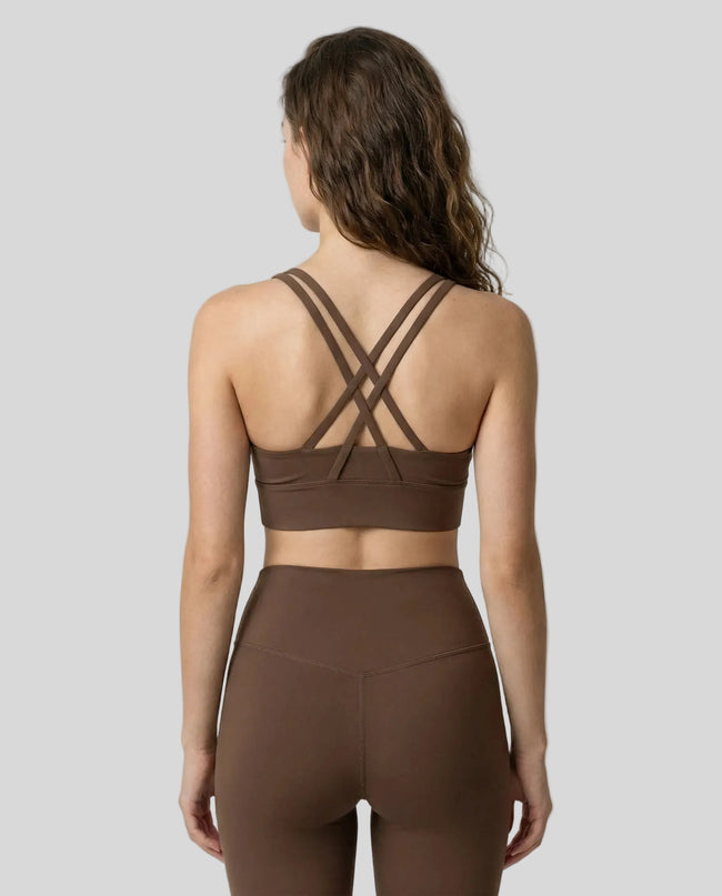 Back view of model a sage AlignCross Studio Sports Bra sports bra highlighting waistline and crisscross straps design