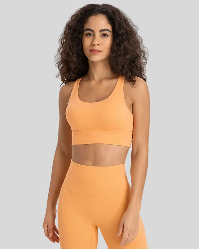 AlignCross Studio Bra in gold worn by model, featuring a scoop neckline and soft supportive fit.