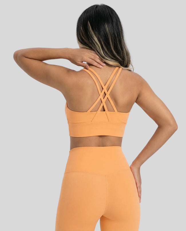 Back view of model a gold AlignCross Studio Sports Bra sports bra highlighting crisscross straps design