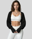Front view of AirLoom Knit Shrug in black layered over neutral activewear
