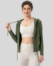 Woman wearing a matcha green hoodie, white sports bra, and leggings on a light gray background