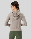 Back view of tan relaxed-fit active hoodie showing hood and fabric