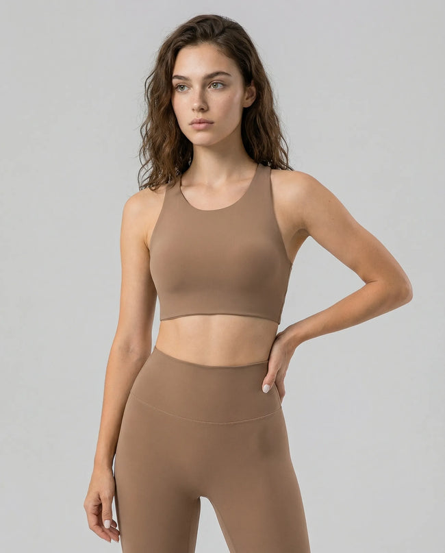 Woman wearing a camel ArcFlow sports bra and camel leggings on a gray background