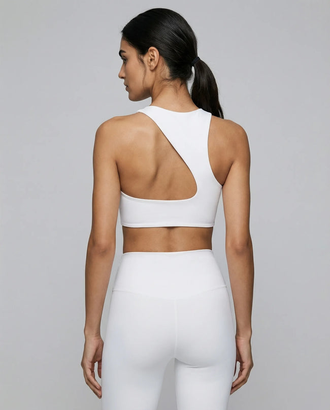Back view of woman wearing a white ArcFlow SportsBbra and white leggings on a neutral background