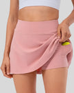 Front left angle view of high-rise pleated sports skirt in blush pink with flowy movement and clean structure