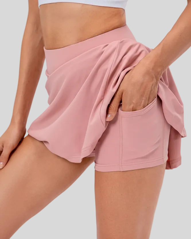 Side view of pleated active skirt in blush pink highlighting lightweight drape and athletic fit