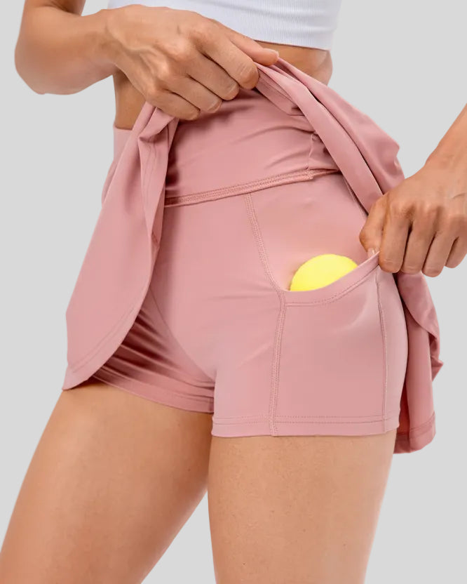 Close-up of built-in shorts and pocket detail on pleated active skirt in blush-pink
