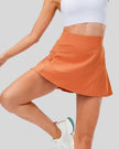 Front angle view of high-rise pleated active skirt in caramel with smooth waistband and lightweight performance fabric