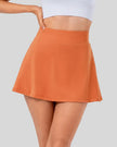 Closeup of high-rise pleated active skirt in caramel with smooth waistband and lightweight performance fabric