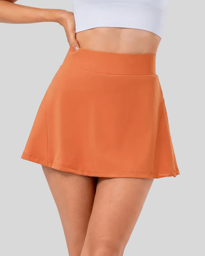 Closeup of high-rise pleated active skirt in caramel with smooth waistband and lightweight performance fabric