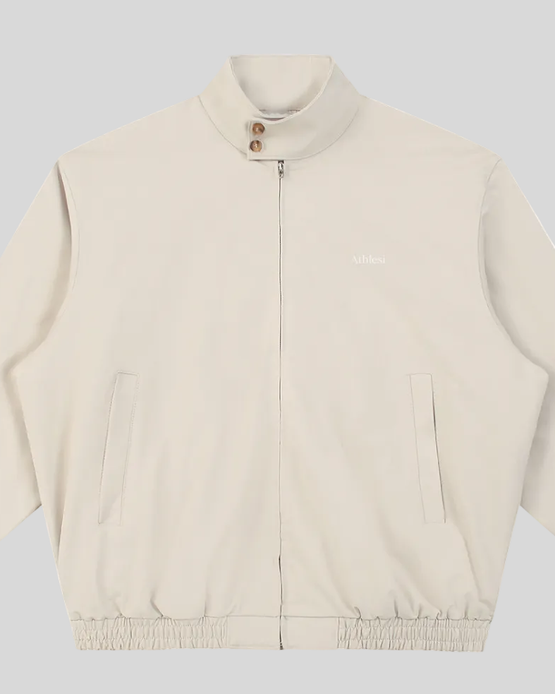 Closeup of stand collar, Athlesi logo, button detail and front zipper on Axis Bomber Jacket in Gray Camel