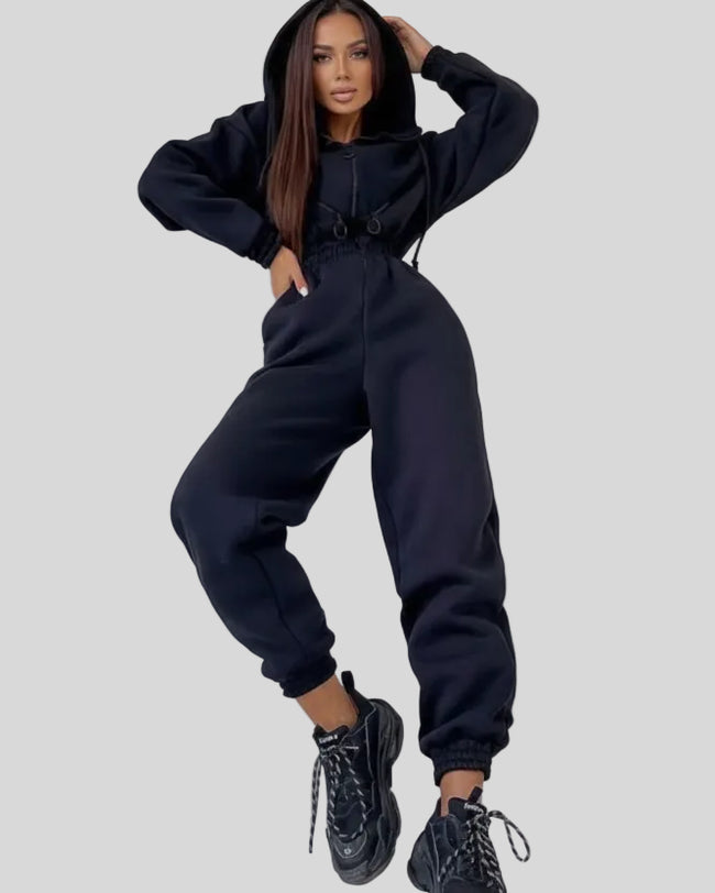 Front angled view of Athlesi Balance Zip Jumpsuit in black, with cinched waist and hooded athleisure design