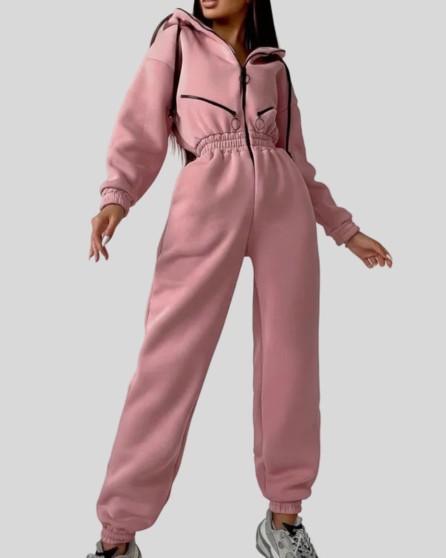 Front angled view of Athlesi Balance Zip Jumpsuit in leather pink, with cinched waist and hooded athleisure design