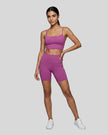 BaseLine Sports Bra and matching biker short in purple, full body front view styled on model