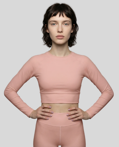 Front view of woman wearing Blush Form Cropped Top in soft blush against a light gray background