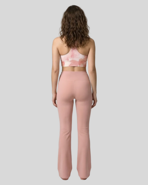 Back view of woman wearing a Blush Form Sports Bra in blush form print and yoga pant in warm sand on a gray background