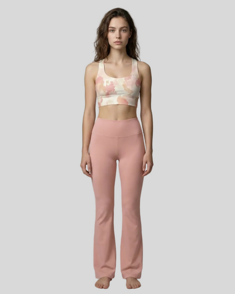 Front view of woman wearing a Blush Form Sports Bra in blush form print and yoga pant in warm sand on a gray background