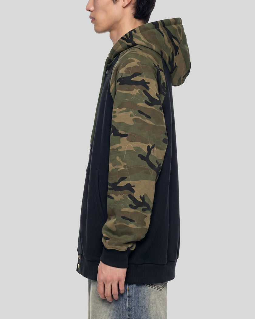 Upper body side view of man wearing Camo Accent Hoodie in black with green camo sleeves