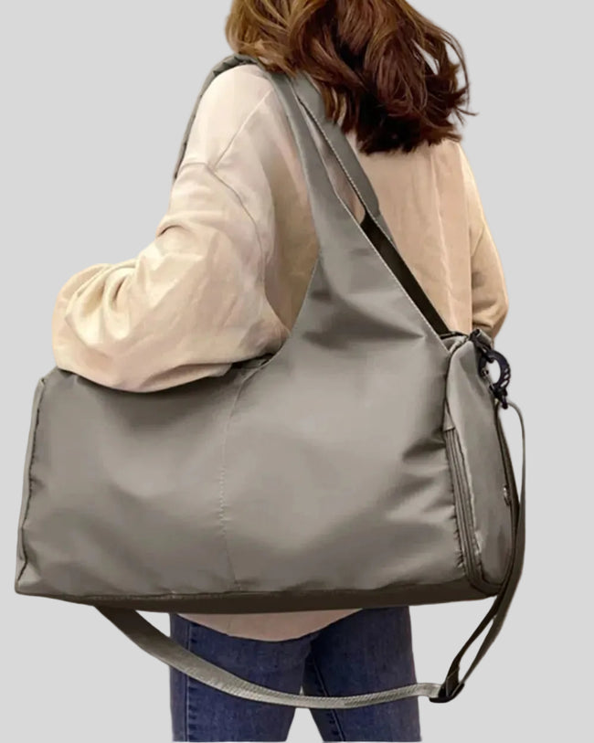 Side angle of model carrying CarryForm Studio Bag in dusty pink styled for gym and everyday use