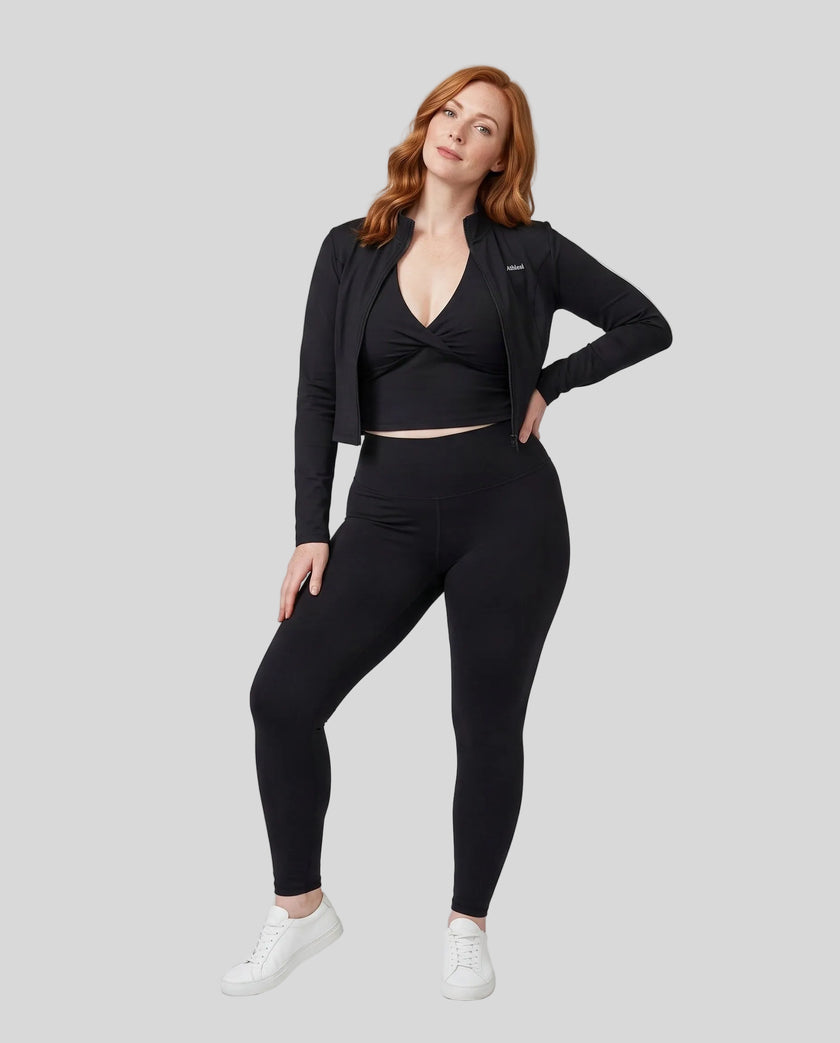Full body front view of woman wearing unzipped Contour Yoga Jacket with matching black activewear