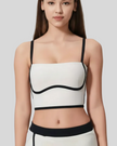 Woman wearing a white and black crop top against a plain background