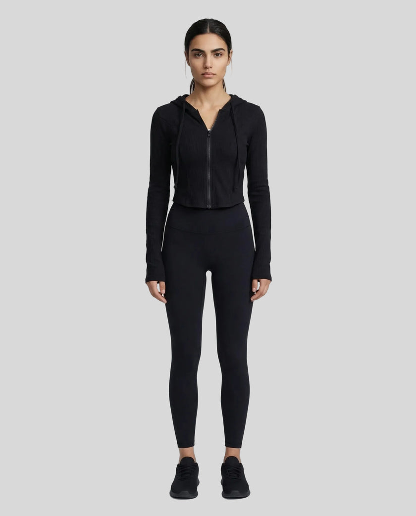 Model wearing a black ContourZip Ribbed Jacket and black leggings in a clean studio setting