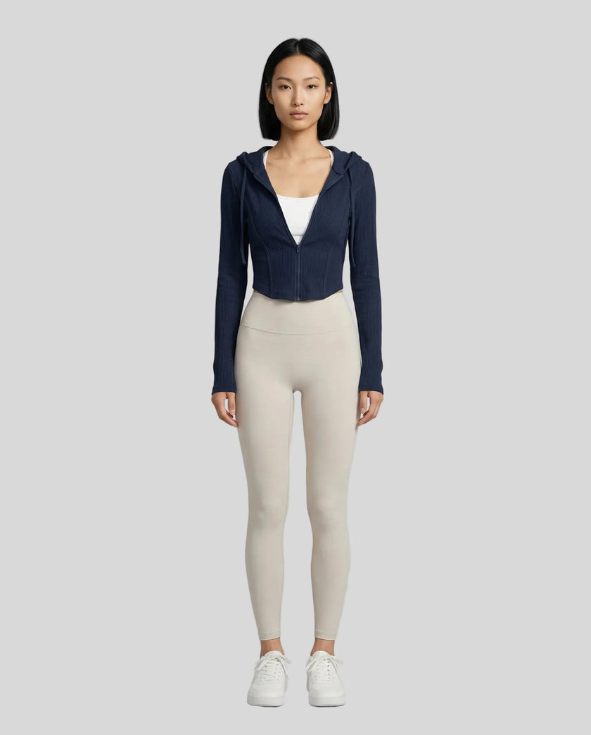 Model wearing a navy ContourZip Ribbed Jacket and white leggings in a clean studio setting