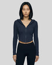 Mid shot of model wearing a navy blue ContourZip Ribbed Jacket and black leggings in a clean studio setting