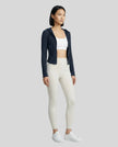 Model wearing an open front navy blue ContourZip Ribbed Jacket and white leggings in a clean studio setting