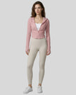 Model wearing a pink ContourZip Ribbed Jacket and white leggings in a clean studio setting