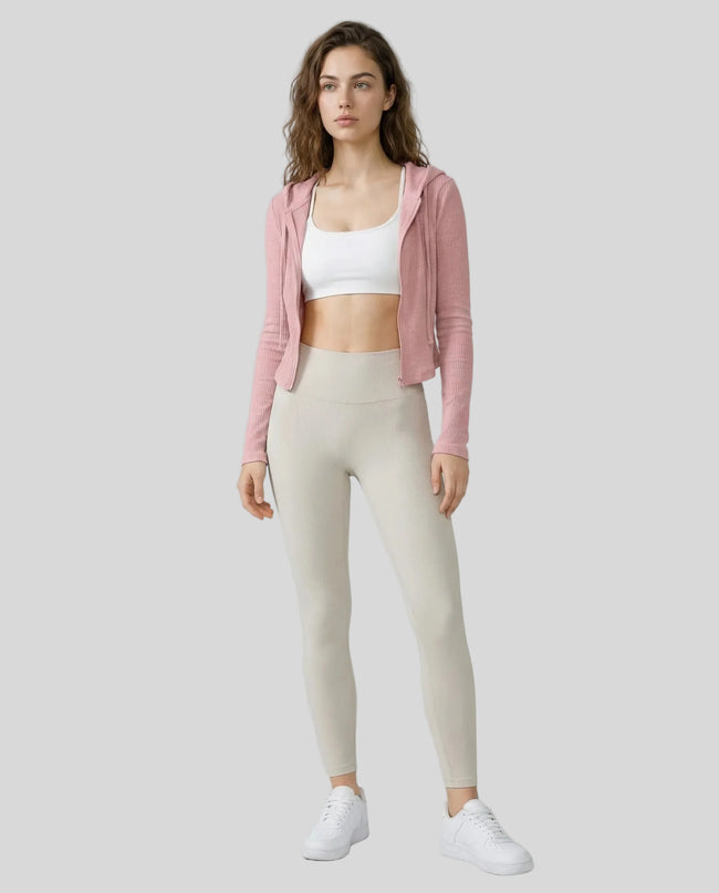 Model wearing an open front pink ContourZip Ribbed Jacket and white leggings in a clean studio setting