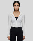 Mid shot of model wearing a white ContourZip Ribbed Jacket and black leggings in a clean studio setting