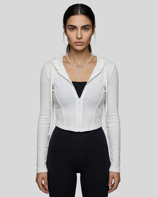 Mid shot of model wearing a white ContourZip Ribbed Jacket and black leggings in a clean studio setting