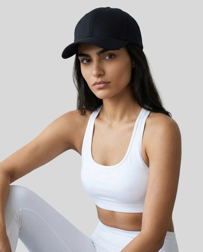 CoreForm Essential Cap in black worn by model in a clean studio setting with a white sports bra and leggings