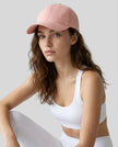 CoreForm Essential Cap in blush pink worn by model in a clean studio setting with a white sports bra and leggings