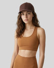 CoreForm Essential Cap in brown worn by model in a clean studio setting with a caramel sports bra and leggings