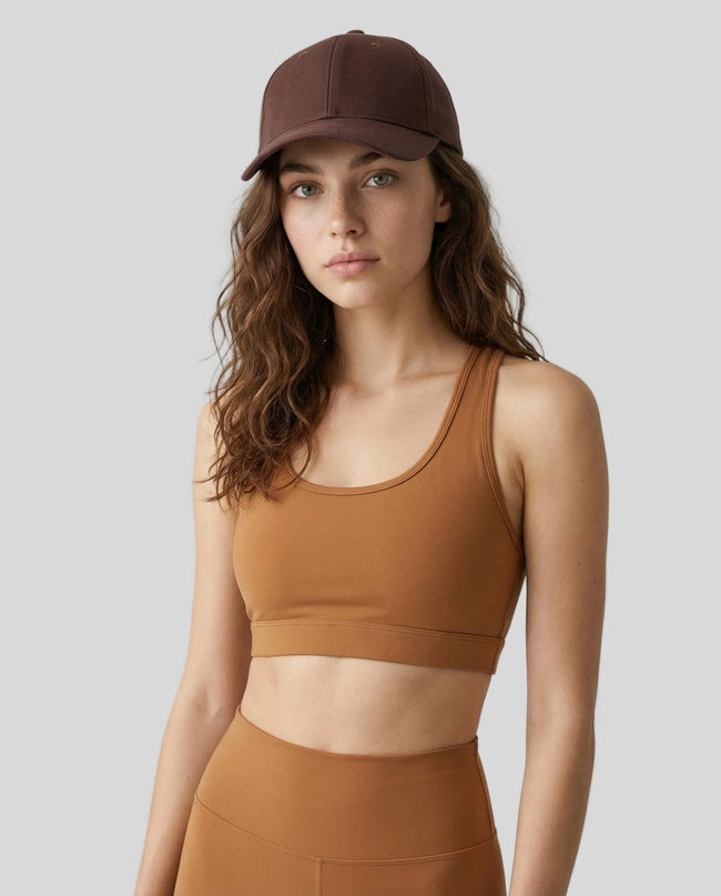 CoreForm Essential Cap in brown worn by model in a clean studio setting with a caramel sports bra and leggings