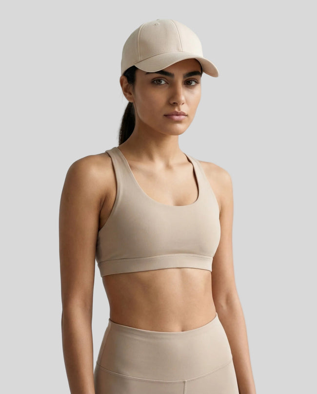 CoreForm Essential Cap in cream worn by model in a clean studio setting with a beige sports bra and leggings