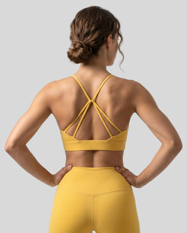 CoreLine Studio Sports Bra in yellow, back view styled on model with strappy detail