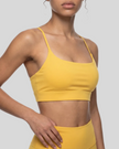 CoreLine Studio Sports Bra in yellow, upper body angled front view