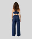 Back view of woman wearing Navy Blue CoreLine Yoga Pants with a matching color sports bra.