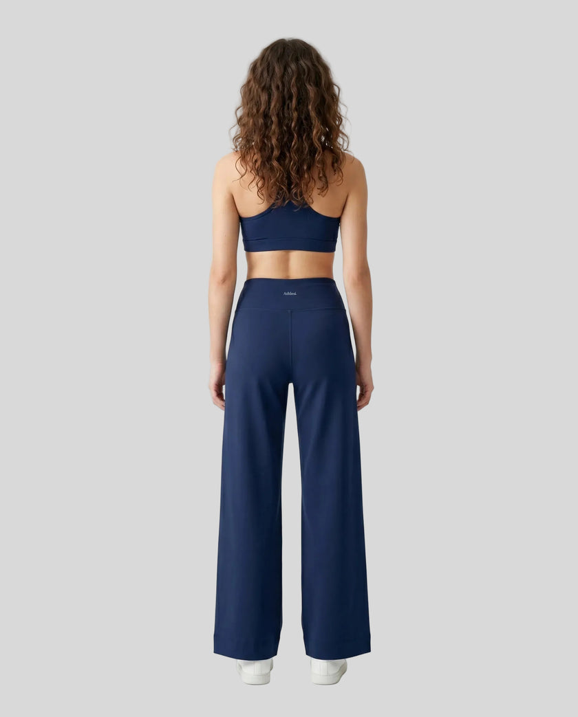 Back view of woman wearing Navy Blue CoreLine Yoga Pants with a matching color sports bra.