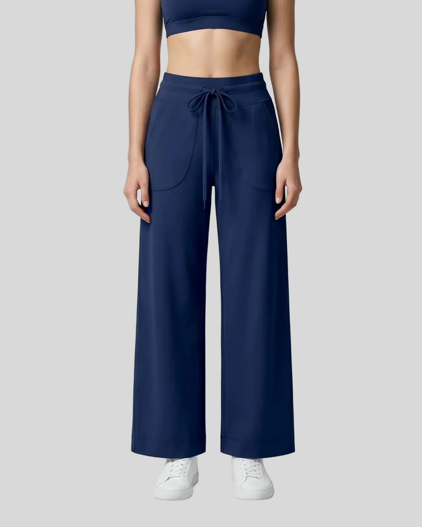 A model wearing navy blue CoreLine Yoga Pants with side pockets, paired with a matching navy crop top and white sneakers