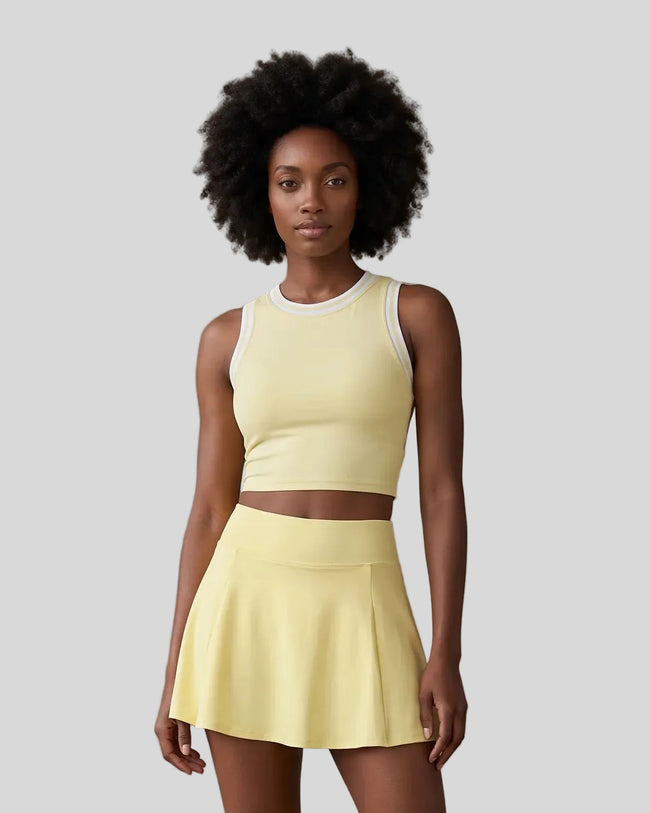 Mid body view of a model wearing the CourtClub A-Line Skirt in Yellow paired with TrackLine Rally Tank Top in Yellow