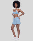 Left-angle view of a model wearing the CourtClub Color Block A-Line Skirt in Sky Blue